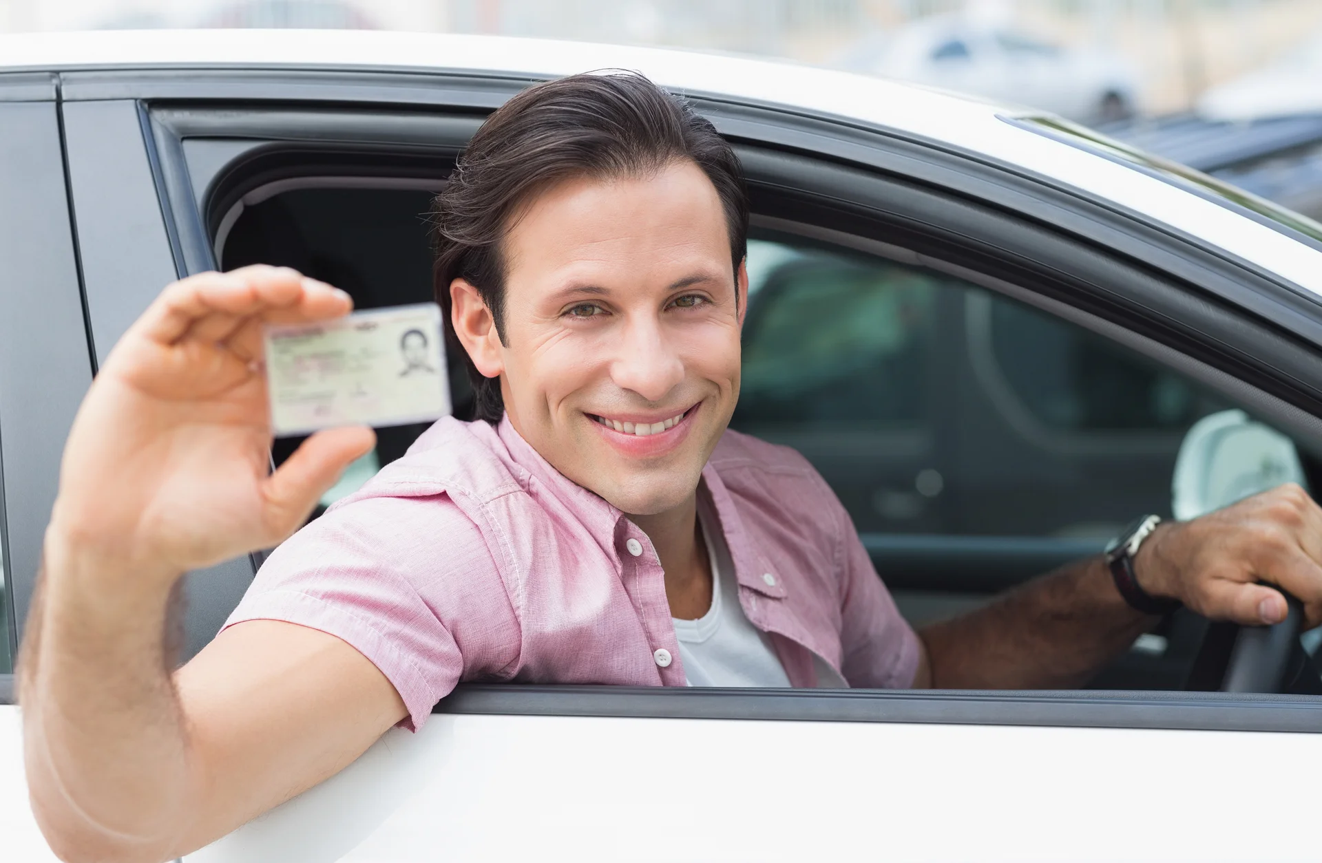 Ein Mann im Auto der seinen Führerschein hochhällt